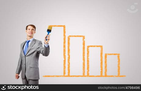 Business growth. Handsome businessman with paint brush in hand