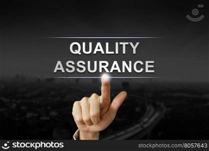business hand clicking quality assurance button on black blurred background
