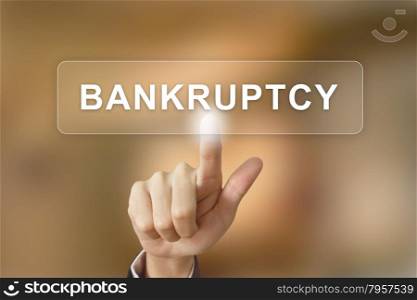 business hand pushing bankruptcy button on blurred background