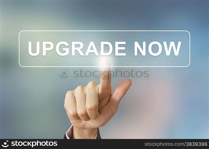 business hand pushing upgrade now button on blurred background