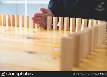 Business hand stops domino continuous overturned meaning that hindered business failure. Stop over this business failure concept.