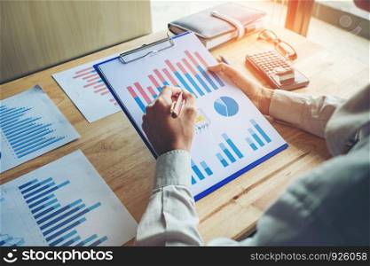 Business hand with a pen pointing on the business paper. Report chart