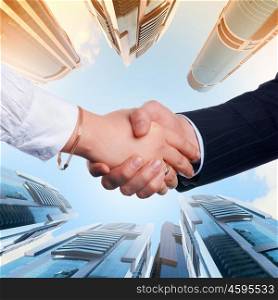 Business handshake. Close up image of hand shake against skyscrapers