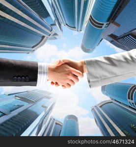 Business handshake. Close up image of hand shake against skyscrapers