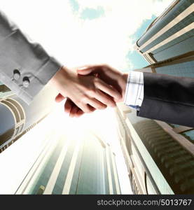 Business handshake. Close up image of hand shake against skyscrapers