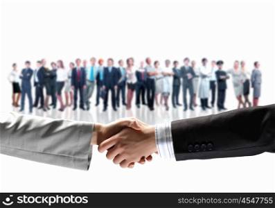 Business handshake. Close-up of human handshake with crowd of people at background