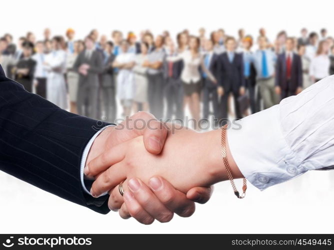 Business handshake. Close-up of human handshake with crowd of people at background