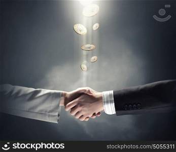 Business handshake. Handshake of business partners and coins at background