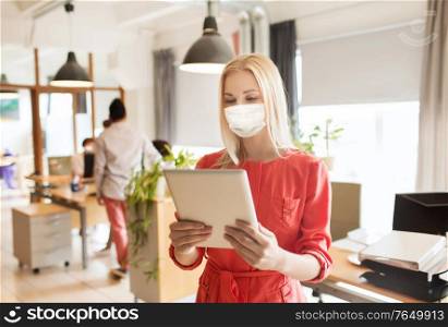 business, health and people concept - businesswoman or creative female office worker wearing face protective medical mask for protection from virus disease with tablet pc computer. female office worker in mask with tablet pc