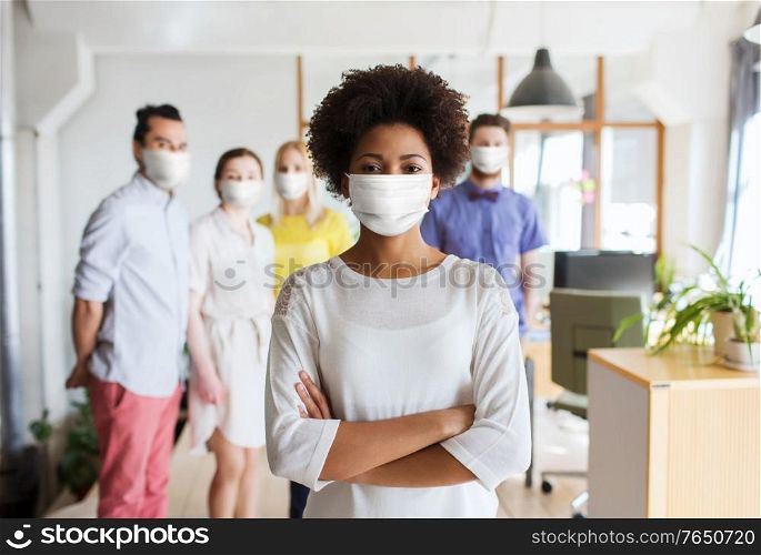 business, health and people concept - young african american woman over creative team wearing face protective medical mask for protection from virus disease at office. woman in mask over creative team at office