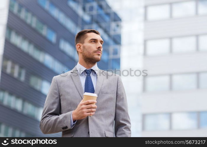 business, hot drinks and people and concept - young serious businessman with paper coffee cup over office building