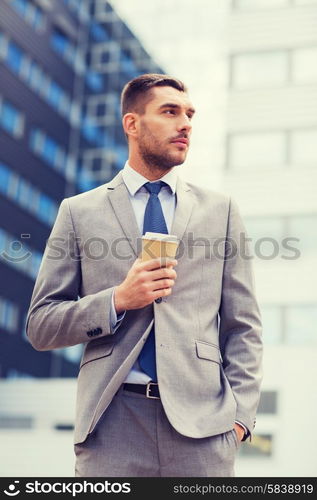 business, hot drinks and people and concept - young serious businessman with paper coffee cup over office building