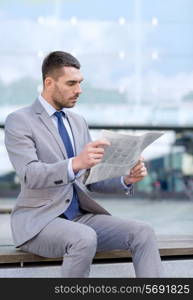 business, hot drinks and people and concept - young serious businessman with newspaper over office building