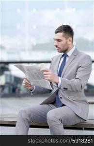 business, hot drinks and people and concept - young serious businessman with newspaper over office building