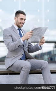 business, hot drinks and people and concept - young smiling businessman with newspaper over office building