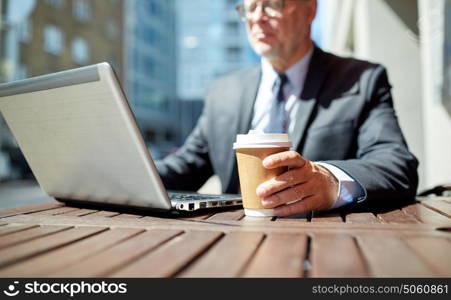 business, hot drinks, technology and people and concept - senior businessman with laptop computer drinking coffee from paper cup outdoors. senior businessman with laptop and coffee outdoors