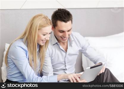 business, hotel, trave and technology concept - smiling couple with tablet pc computer in hotel room