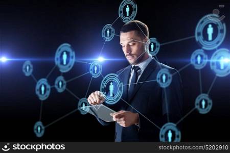 business, human resources and modern technology concept - businessman working with transparent tablet pc computer and with virtual network contacts over black background. businessman with tablet pc and network contacts