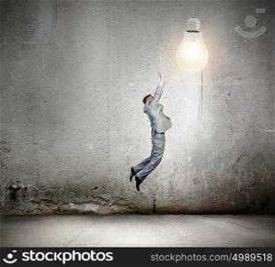 Business idea. Image of businessman jumping to catch light bulb