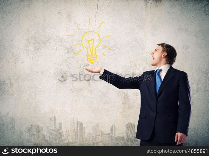Business idea. Young businessman holding electric bulb in palm