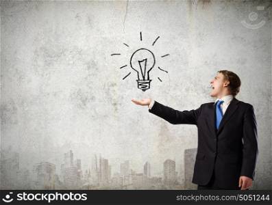 Business idea. Young businessman holding electric bulb in palm