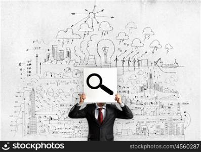 Business ideas. Businessman hiding his face with sheet of paper with sketches at background