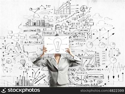 Business ideas. Businesswoman hiding her face with sheet of paper with sketches at background
