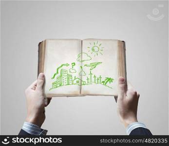 Business ideas. Close up of businessman hands holding opened book with sketches