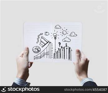 Business ideas. Close up of businessman hands holding opened notepad with sketches