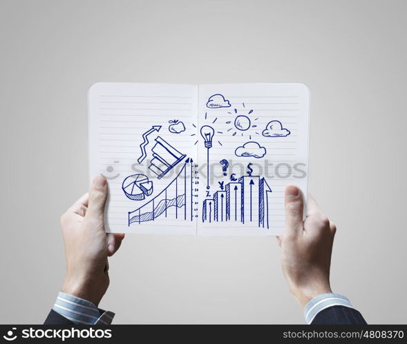 Business ideas. Close up of businessman hands holding opened notepad with sketches