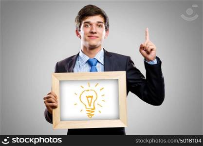 Business ideas. Handsome businessman holding wooden frame with words