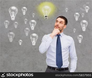 business, ideas, inspiration and people concept - handsome businessman looking up and thinking over concrete background with light bulbs