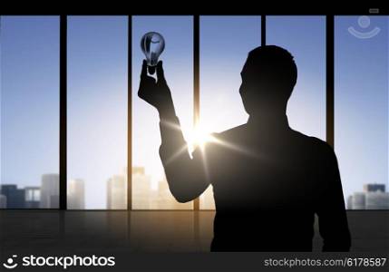 business, inspiration, idea and people concept - silhouette of businessman holding light bulb over office window background