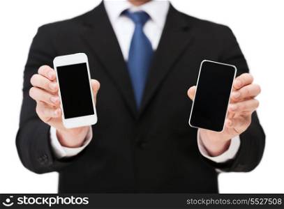 business, internet and technology concept - businessman showing two smartphones with blank black screens