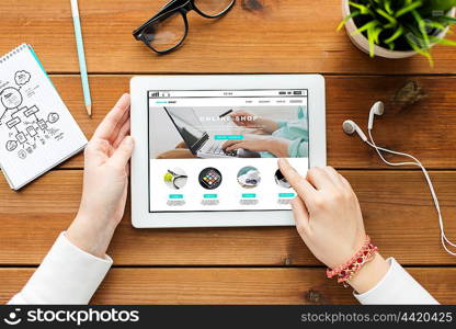 business, internet shopping, technology and people concept - close up of woman with online shop web page on tablet pc computer screen on wooden table