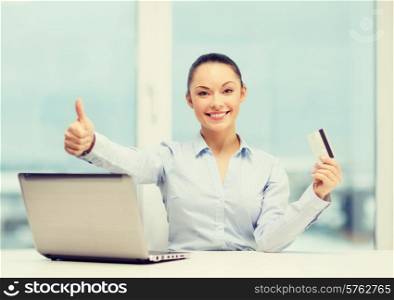 business, investing and technology concept - businesswoman with laptop and credit card in office showing thumbs up