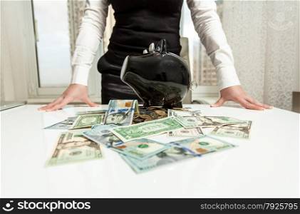 Business lady behind table with piggy bank and money