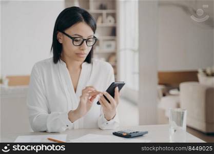 Business lady is appointing meeting, texting on smartphone. Young caucasian businesswoman in glasses and white blouse is working remote from home. Manager, secretary or freelance worker at workplace.. Business lady is appointing meeting, texting on smartphone. Manager or secretary at workplace..