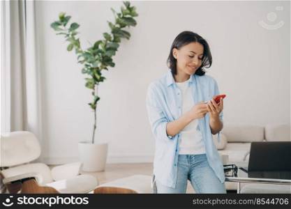 Business lady is chatting on phone and smiling. Young mixed race woman in casual outfit is working at home office. Confident professional at workplace. Remote work and communication concept.. Business lady is chatting on phone and smiling. Remote work and communication concept.