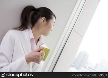 Business lady looking at outside having a coffee cup