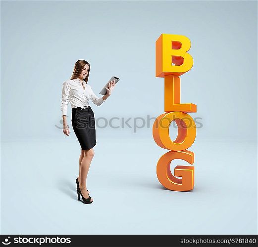 Business lady with tablet pc stands near word blog. Idea concept.