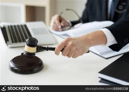 business lawyer hand holding justice hammer at office with laptop, book and documents.