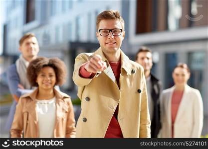business, leadership and hiring concept - man pointing finger at you over international group of people on city street. businessman pointing finger over people on street
