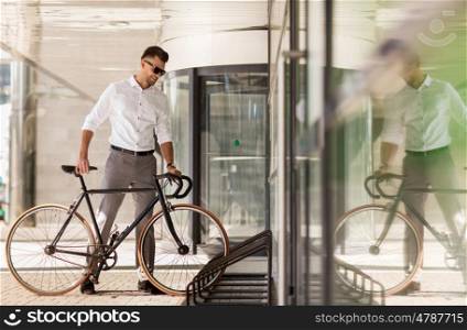 business, lifestyle, transport and people concept - young man parking bicycle on city street