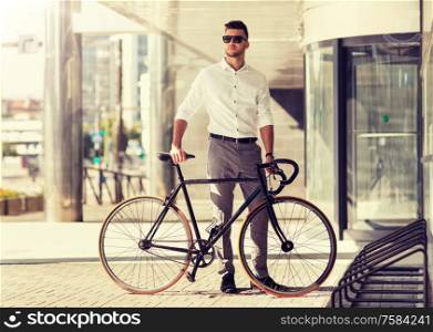 business, lifestyle, transport and people concept - young man parking bicycle on city street. young man parking his bicycle on city street