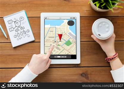 business, location, education, technology and people concept - close up of woman with gps navigator map on tablet pc computer screen and coffee on wooden table with gps navigator map on screen
