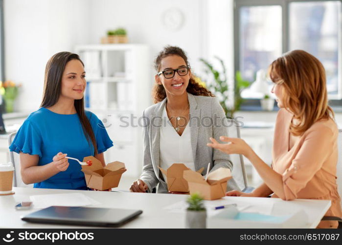 business lunch and people concept - happy businesswomen eating take out food and talking at office. happy businesswomen eating take out food at office. happy businesswomen eating take out food at office