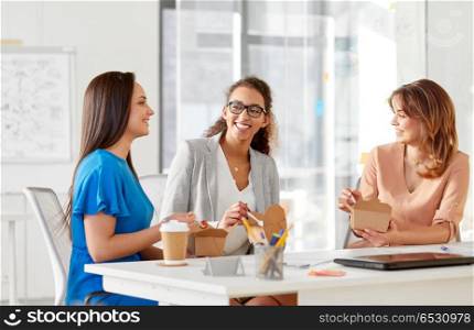 business lunch and people concept - happy businesswomen eating take out food and talking at office. happy businesswomen eating take out food at office. happy businesswomen eating take out food at office
