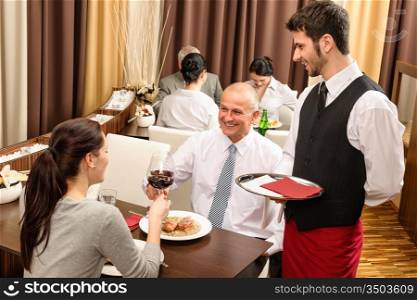 Business lunch executive people toast with red wine young waiter serve