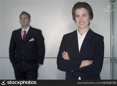 Business man and business woman pose as they stand in front of camera